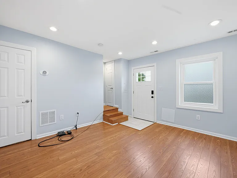 Spacious Living Space Featuring Warm Hardwood Floors and Natural Light Filtering