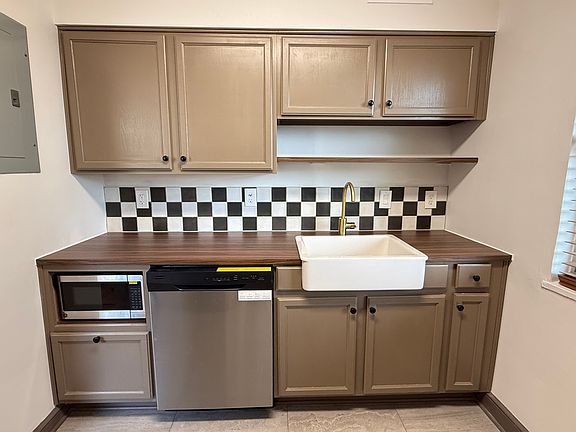 Farmhouse sink, ceramic backsplash, freshly painted cabinets, new plumbing fixtures, built-in microwave, and new dishwasher.