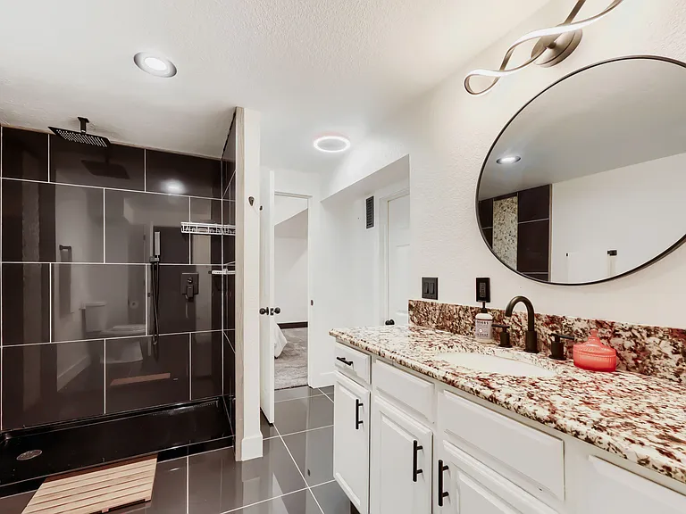 Updated bathroom with walk-in tile shower, double-sink vanity, ample storage, and plenty of space for shared bathroom.