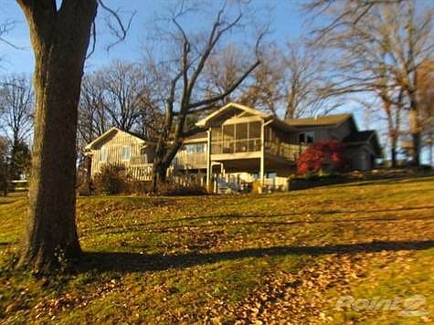 Angle view in evening light shows landscape detail and screened porch over the patio.