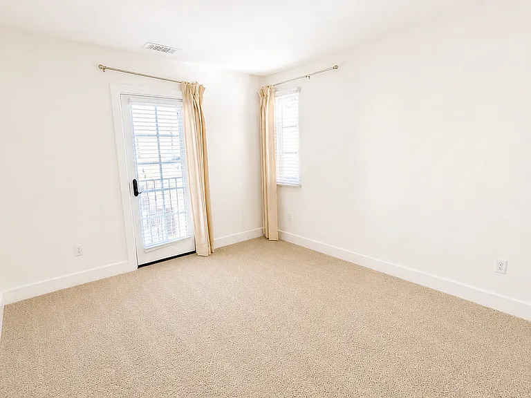 Spacious guest bedroom with private balcony access and abundant natural light