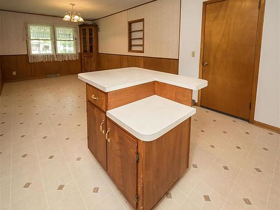 View of island with cabinets over looking dining room with built ins.