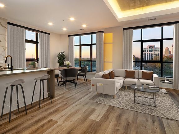 Kitchen, living, and dining areas with hard surface flooring throughout and floor-to-ceiling windows