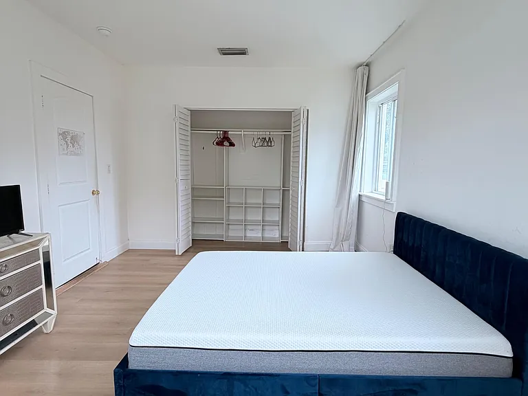 Furnished bedroom with a full bed, large window, and an organized closet system for convenient storage.