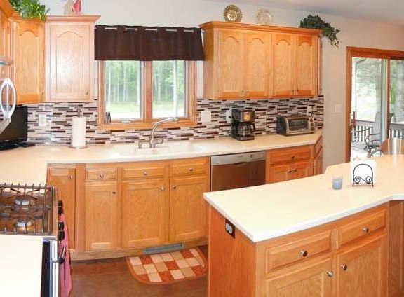 The open and updated eat-in kitchen has newer flooring, backsplash, and stainless steel appliances.  The corian counters are in great shape and all the cabinets were custom built and are solid wood with 7/8" plywood shelving! 