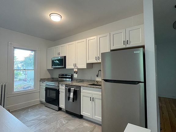 Tiled kitchen with granite countertops and new appliances.