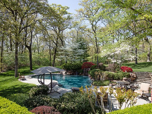 Backyard oasis features gorgeous sparkling Swimming Pool with waterfall in private, professionally-maintained, wooded setting.