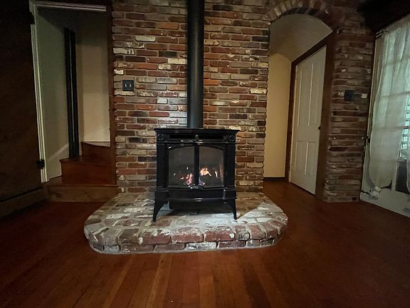 Gas fireplace, stairs behind, and basement entry with storage space
