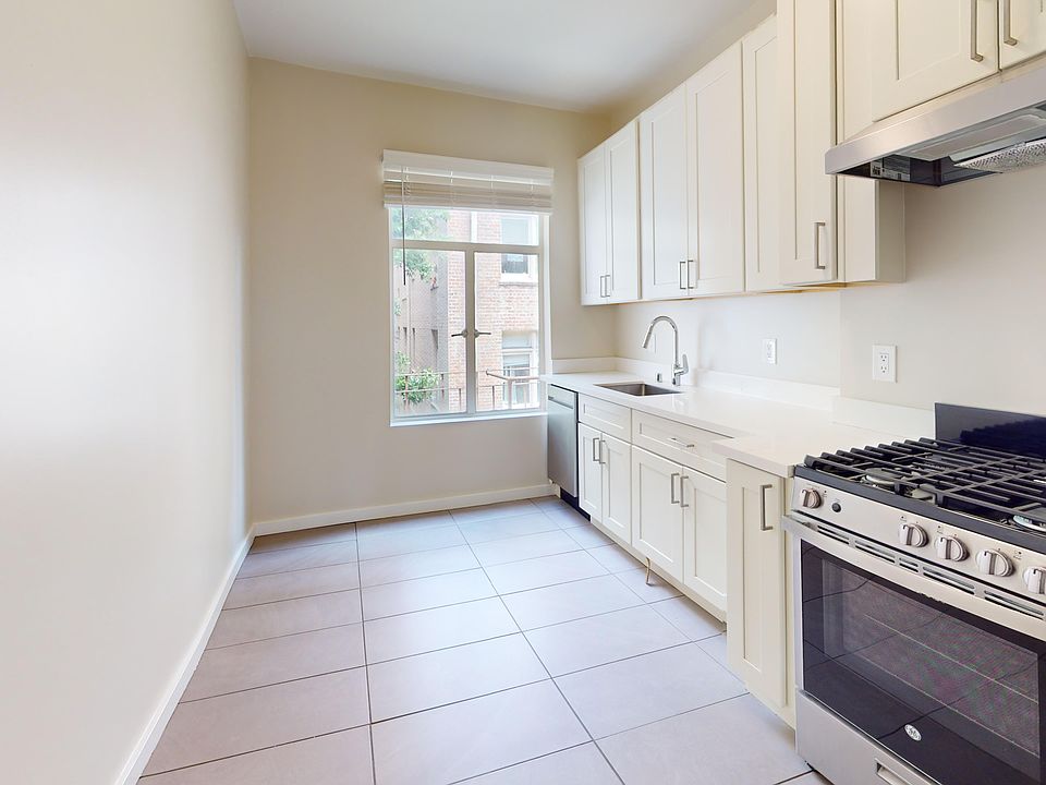 Modern kitchen featuring cabinets, stainless steel appliances, and a window for natural light, with tiled flooring.