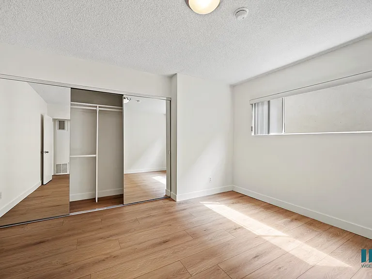 Bedroom with Vinyl Flooring and a Mirrored Closet
