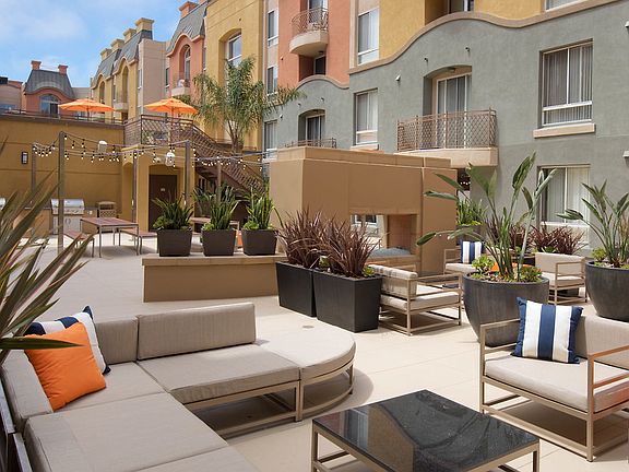 Outdoor fireplace with lounge chairs, picnic tables, and planters.