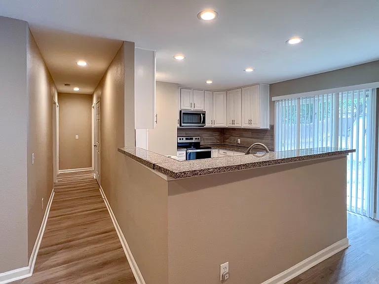 Hallway just off the kitchen leads to the two secondary bedrooms and second full bath, creating nice separation from the primary suite.