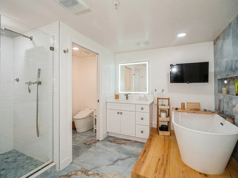 Primary bathroom has a soaker tub with TV, separate shower, dual sinks, makeup vanity, toilet closet
