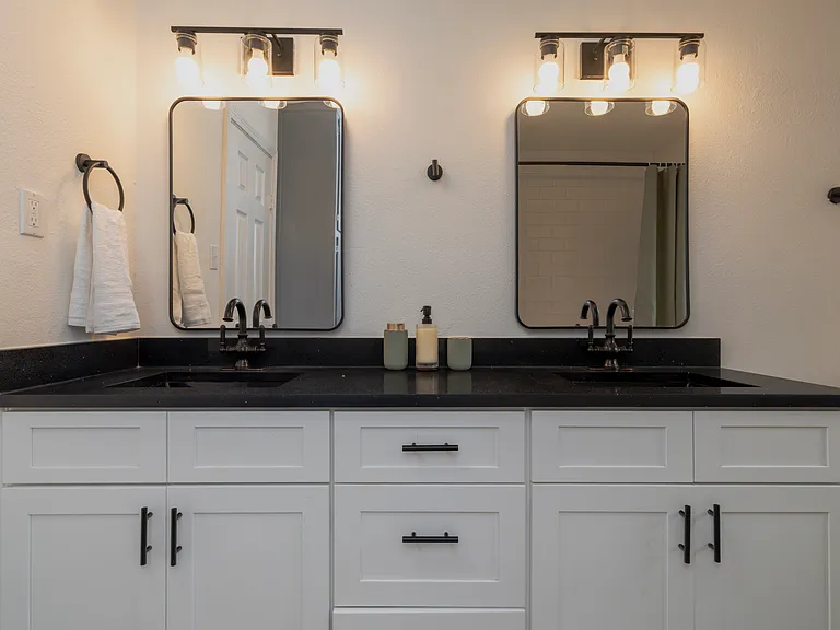 Full bathroom with double sinks and shower-tub combo attached to bedroom 1.