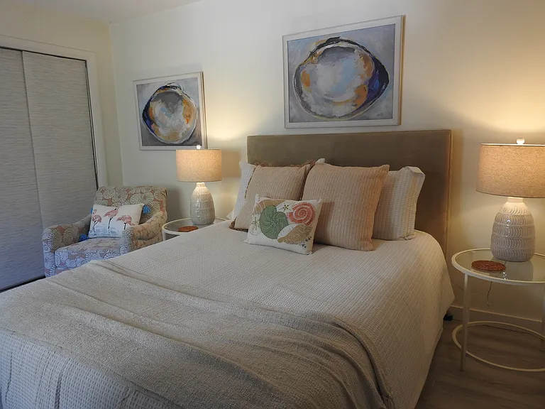 Spacious guest room with comfy queen bed, cozy club chair and soft lighting.