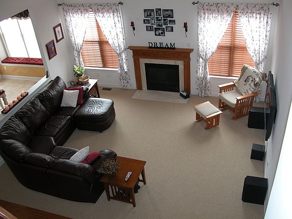 Family room with berber carpet, stained oak mantle, open to kitchen