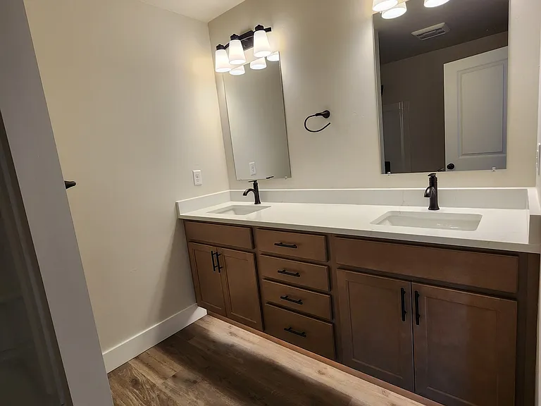 Primary suite bathroom with double sink and toe-kick lights.