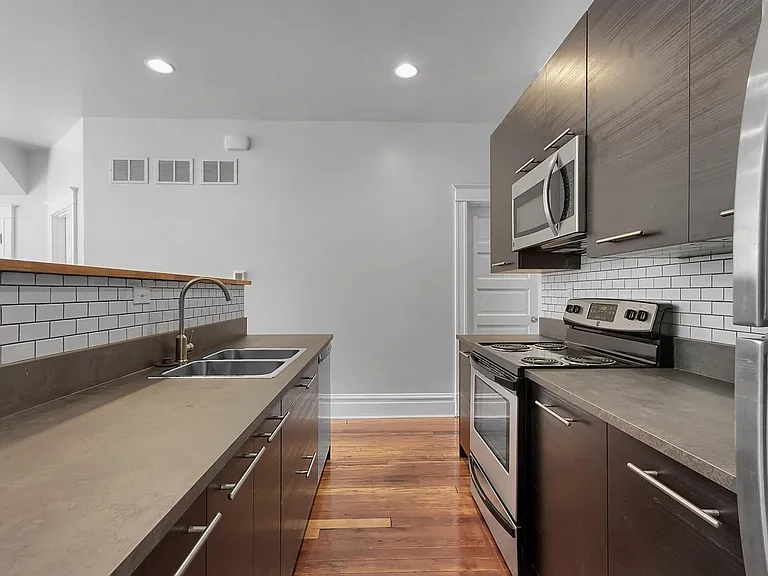Kitchen - salvaged hardwood floors, stainless steel appliances, tiled backsplash, venetian blinds