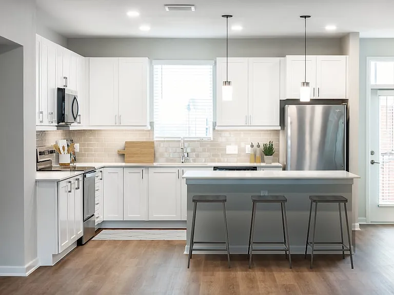 Finish Package I townhome kitchen with stainless steel appliances, white cabinetry, grey tile backsplash, white quartz countertops, and hard surface flooring