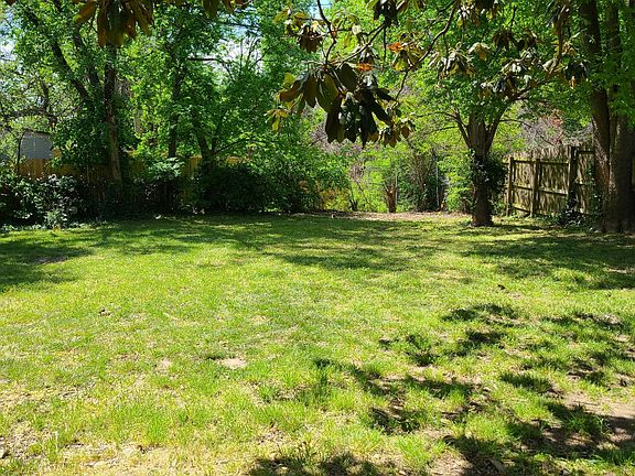 Fenced backyard with several trees for shade.