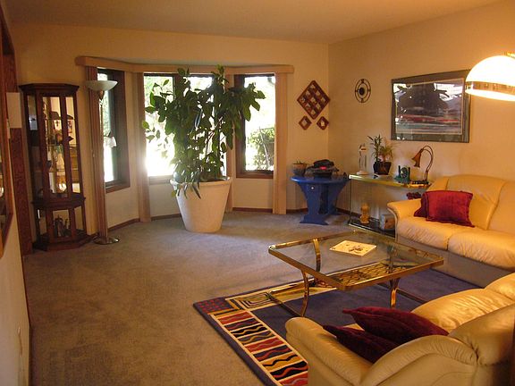 The large living room has neutral decor, and a large bay window.