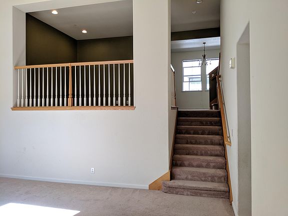 View from front door. Large living room with high vaulted ceilings. Stairs go up to family room, dining, room, and kitchen.