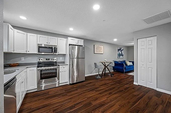 Modern open-concept kitchen with sleek stainless steel appliances, cozy dining nook, and inviting living space with wood flooring.
