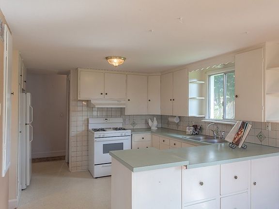 Well thought-out kitchen with the classic look and feel of the 1950s, loads of cabinets, gas range oven, tile back splash, nearby canning cellar and large opening window viewing backyard. 