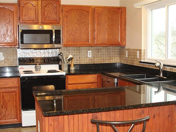 Black granite countertops  highlight the updated kitchen with a matching granite/composite double bowl sink.