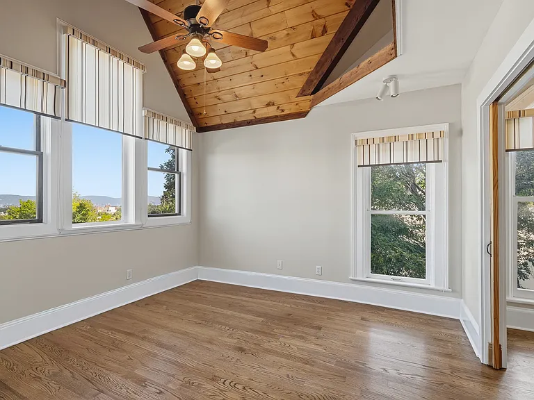 The front bedroom features windows on all sides, gorgeous light from every exposure, large closet, fan and original hardwood floors.