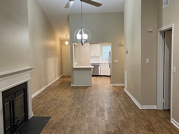 View of the living room with wood burning fireplace that flows to dining area and flows to open kitchen