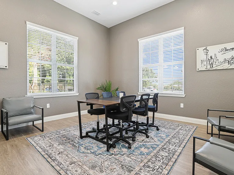 Bright, modern meeting room with a chic table, comfortable chairs, elegant wall art, and large windows offering natural light.