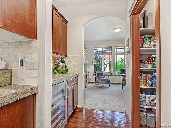 Pass-through between living room and kitchen has walk-in pantry, wine fridge, cabinetry