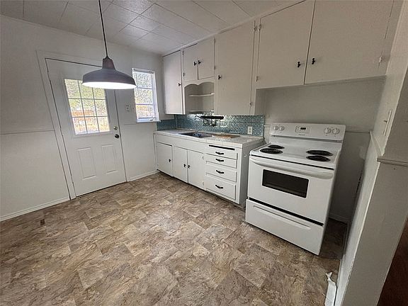 Kitchen featuring white cabinetry, a white electric range, a white door with window panes, and patterned tile flooring