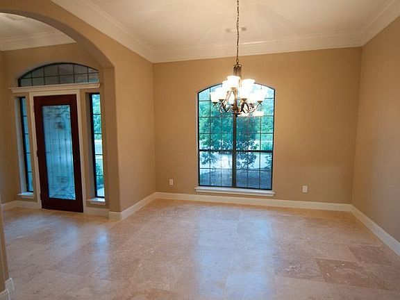 View of travertine floors, elaborate dining room chandelier, & arched entries.