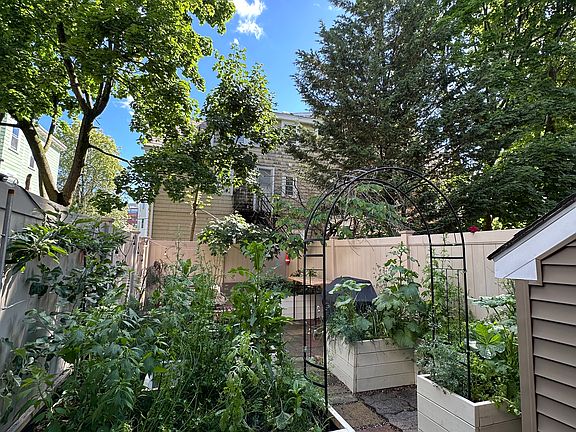Renovated Large Backyard with three Raised Beds, outdoor couch, and outdoor table and chairs. A working gas grill is included.