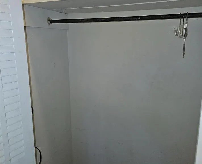 Reach-in closet provides hanging space and an overhead shelf for storing clothing, shoes, and personal items.