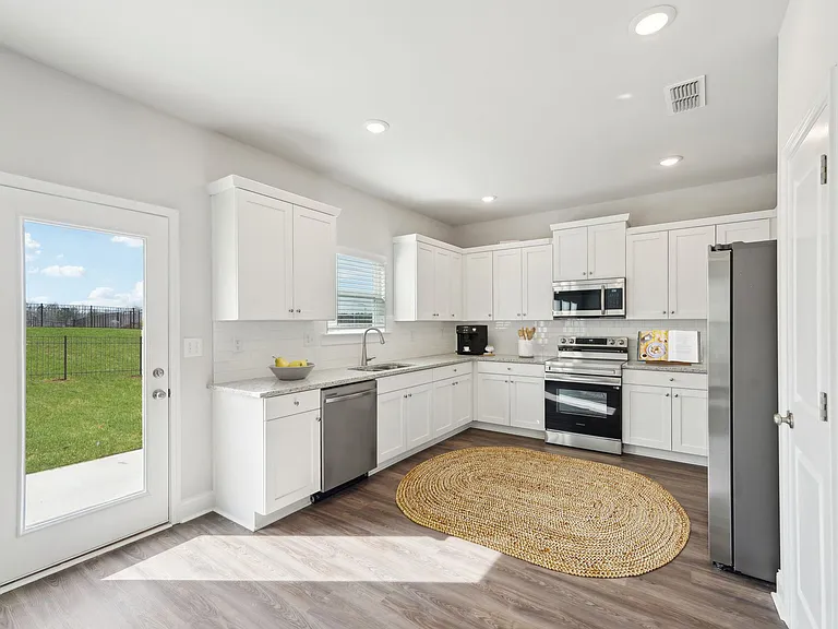 Modern kitchen with white cabinetry, stainless steel appliances, and direct patio access.