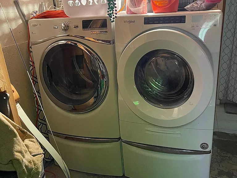 Extra large gas dryer/washer on pedestals in storage room