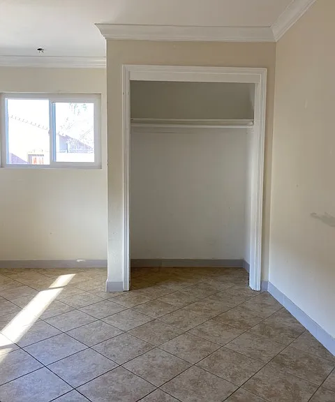 View of master bedroom. There is a ceiling fan in this room. His and Her closets. Closet doors are there now.