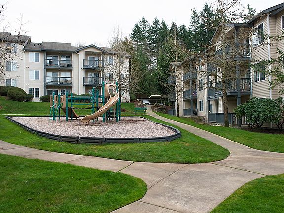 Exterior of apartment community with walking paths, playground, and green space.