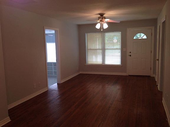 Living room with large windows, hardwood floors, ceiling fan