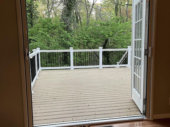 French doors from living room lead to large deck and wooded scenery.