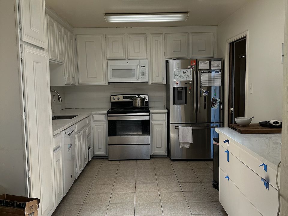 A different view of kitchen looking at the stove and refrigerator, including opposite countertop/drawer.