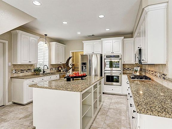 The kitchen was updated in 2013 with granite counter tops, lighting and stainless appliances. Note the double over, perfect for entertaining. There is also a GE Monogram Wine Reserve in the island.