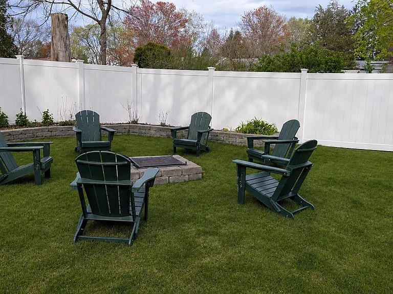 Fire pit and Adirondack chairs in partially fenced yard