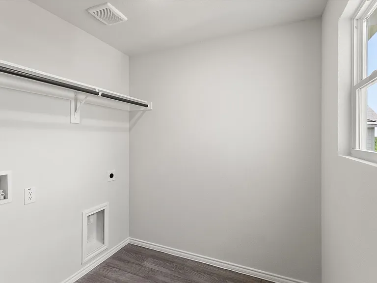 Utility space featuring a single-hung window, wood-finish flooring, a wall-mounted clothing rod with shelving, and appliance hookups