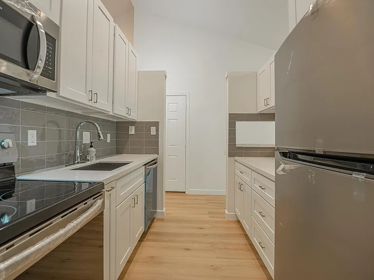 View of your galley Kitchen with all new appliance, new cupboards and kitchen tops taken from the back hallway looking out towards the front door and front hallway.