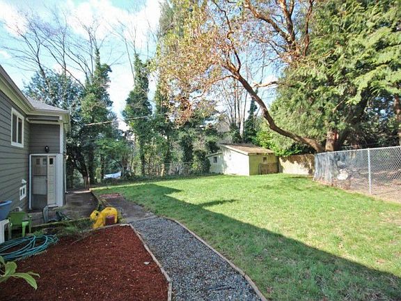 This charming back yard has a fenced in dog area to the right and a utility shed in the corner. You even have planting beds for all those spring flowers. Note the rear entrance into the home for easy access upstairs or down.