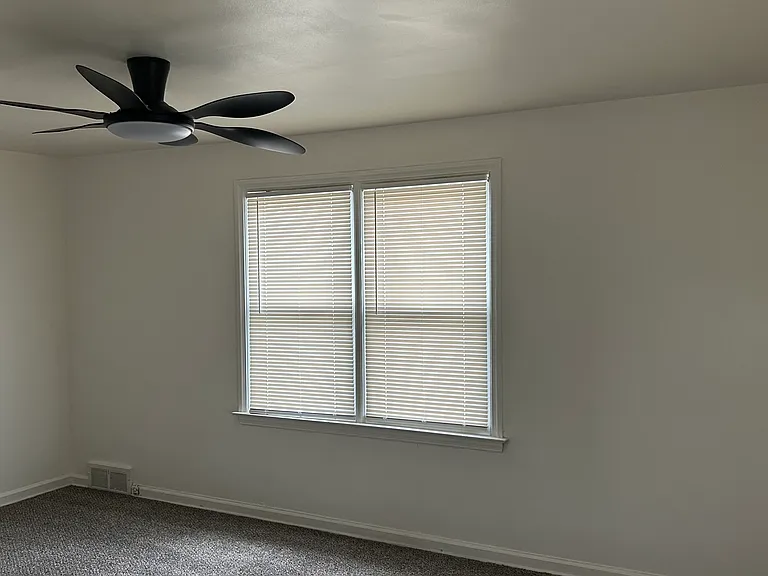 Generously sized bedroom with large windows and updated ceiling fan.